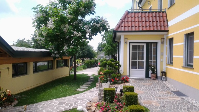 Kerndlerhof main entrance, © Kerndlerhof Entrance to a yellow building with a well-kept garden and paved path.