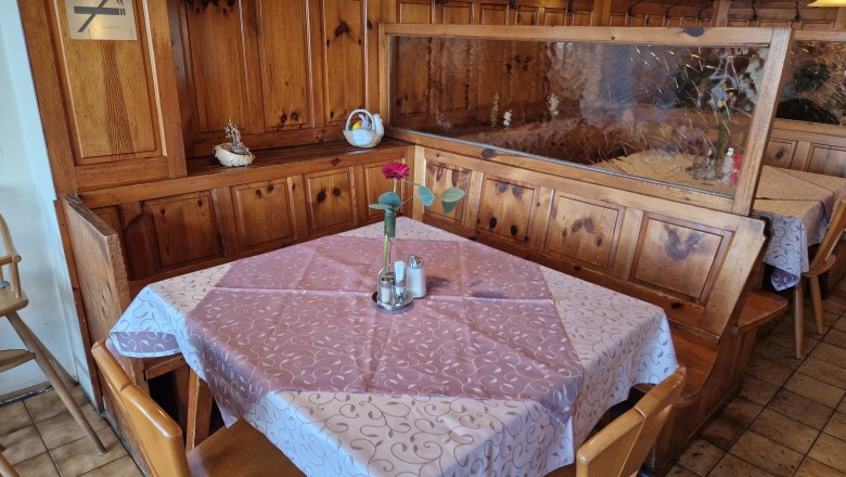 Guest room, © Karin Stranz A cozy table in a rustic guest room with wood paneling, tablecloth and a vase with a flower.