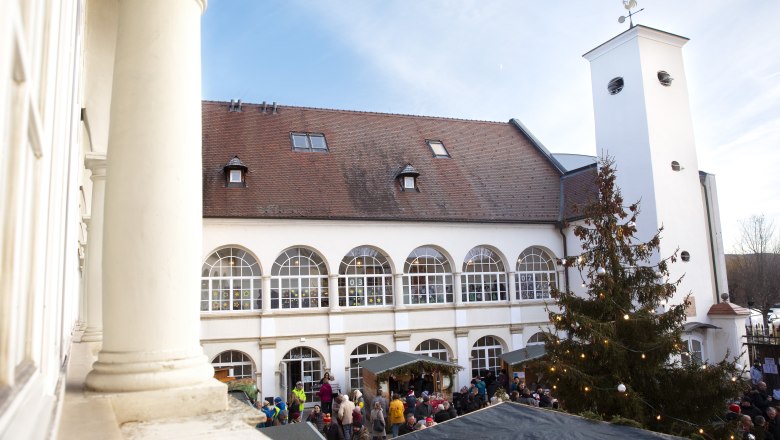 Katzelsdorf Castle at the Christmas market, © Wiener Alpen/Stefanie Reisenbauer Exterior view of a Schloss Hof with Christmas market and decorated tree in the courtyard.