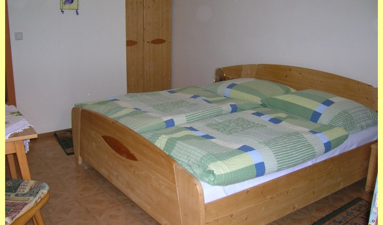 Room, © Familie Mörtinger One bedroom with a double bed, wooden furniture and green bed linen.