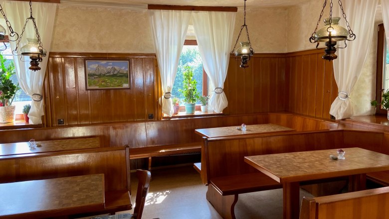 Blunzenwirt restaurant, © Wiener Alpen Cozy dining room with wooden furniture, white curtains and plants on the windowsill.
