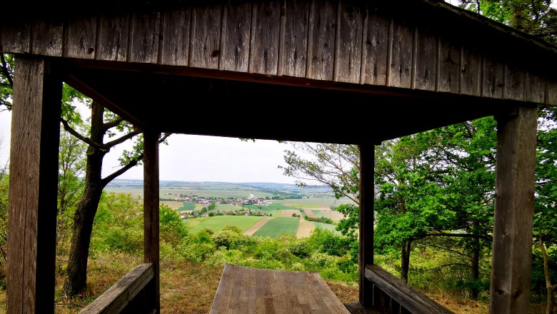 Hollenstein lookout point, © Weinstraße Weinviertel Wooden hut with view of fields and village in the distance.