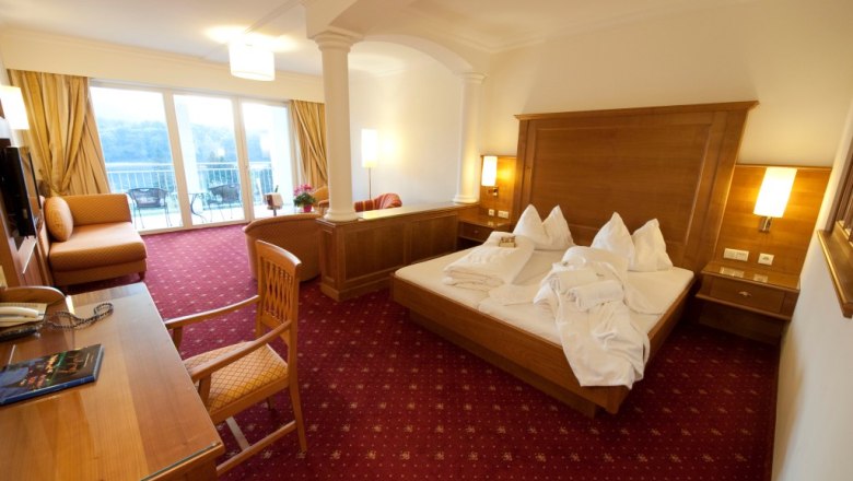 Premium bon-vivant rooms Smaragd, © Gartenhotel Pfeffel GmbH Hotel room with double bed, desk and balcony with view.