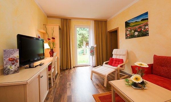 Poppy room, © Johann Frank Cozy room with red accents, TV, sofa, armchair and view of the garden through a glass door.