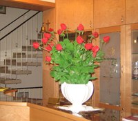 Inside, © Rosner A flower arrangement with red roses in a white vase on a table in an interior.
