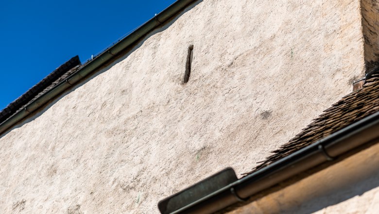 Fortified church Bad Schönau, © Wiener Alpen, Christian Kremsl Close-up of a white wall with an embrasure gutter and blue sky in the background.