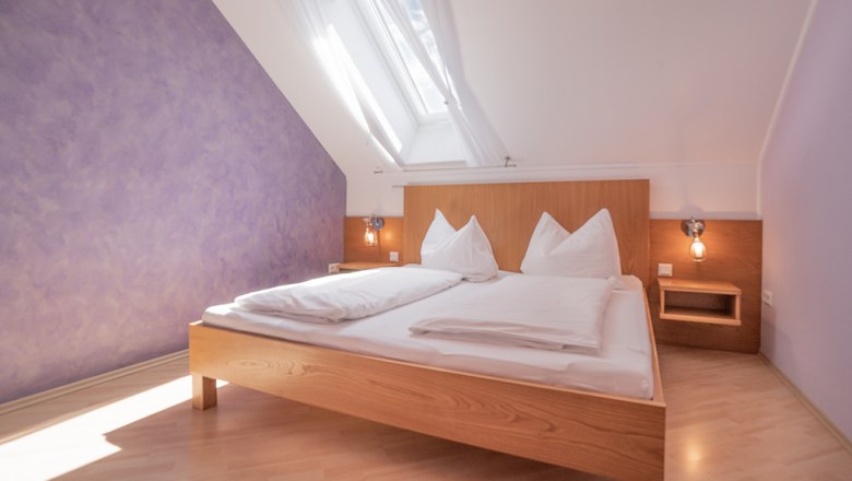 Rooms to feel good in, © Stefan Jurecek Bright bedroom with skylight, purple wall and wooden bed.