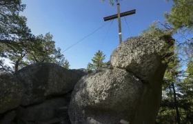 High stone, © Matthias Schickhofer Large rocks with a wooden cross on a wooded hill.