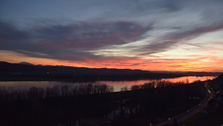 Sunset2, © Gasthof Donaublick Sunset over a river with trees and a road in the foreground.