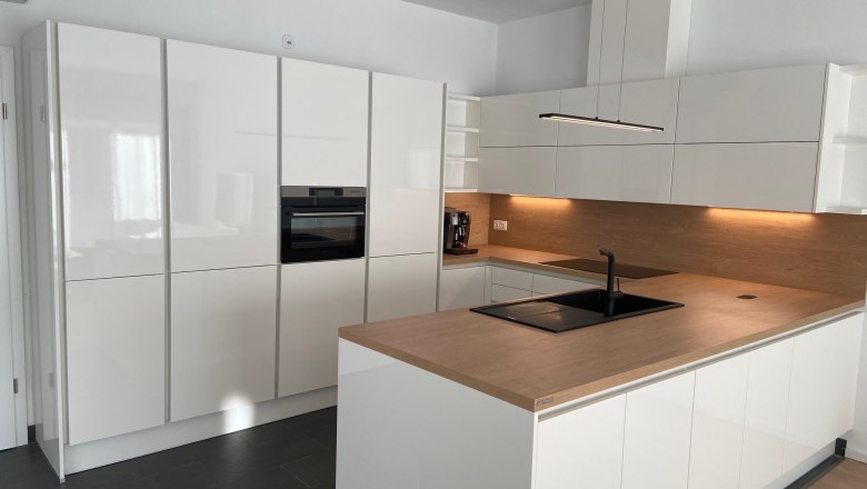 Kitchen, © Wiener Alpen Modern kitchen with white high-gloss cabinets, wooden worktop and built-in oven.