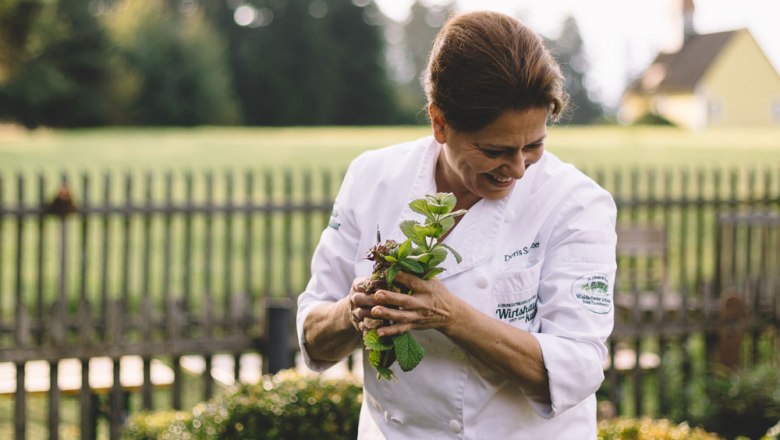 Regional cuisine with home-grown herbs, © Niederösterreich Werbung/Mara Hohla A cook in a white uniform keeps fresh herbs in a garden.