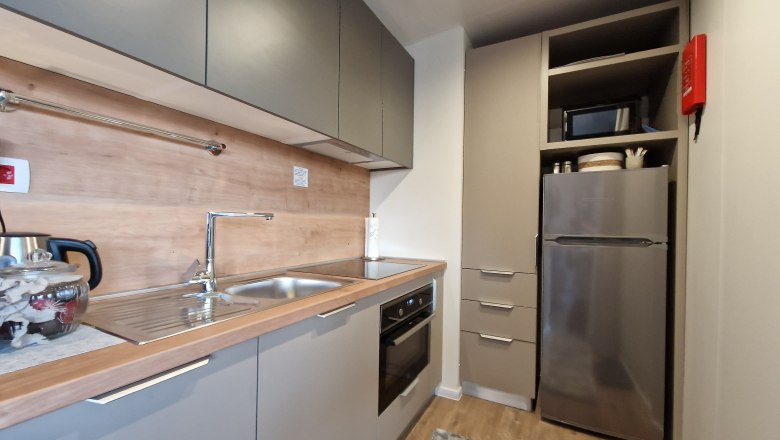 Kitchen Johannesbachklamm Chalet, © Johannesbachklamm Chalet Modern kitchen with gray cabinets, stainless steel sink, stove and refrigerator.