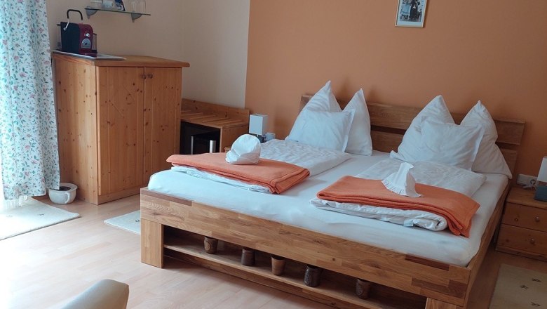 Dormouse room, © Karoline Schmidt Cozy bedroom with double bed, wooden furniture and orange wall.