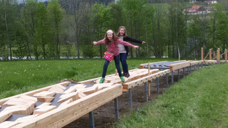 Motor skills park, © rosinger Two girls balance on a wooden course outdoors.