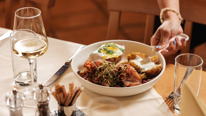 Wine.restaurant Neustifter, © Weinviertel Tourismus / Michael Reidinger A plate of food and a glass of white wine on a laid table.