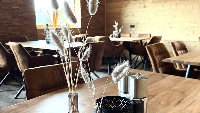 Being "at home" in Hollenthon, © Anita Gradwohl, dahoam Cozy room made of wood, decoration on wooden table, lettering 'dahoam' on the wall.