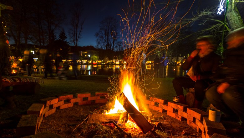 Aspanger Advent market at the pond, © wieneralpen-kremsl Campfire at the Aspanger Advent market with people in the background.