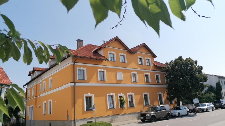 Bed and breakfast Csenar, © Wiener Alpen Yellow building with red roofs, surrounded by trees and parked cars.