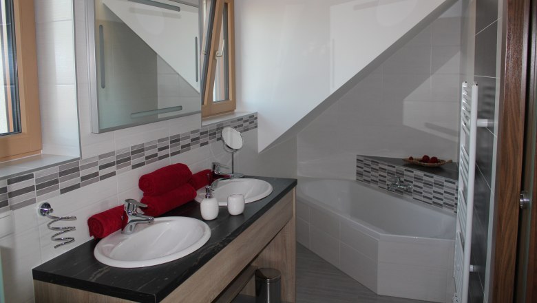 Guesthouse Woditschka, © Fam. Woditschka Modern bathroom with double washbasin, bathtub and red towels.