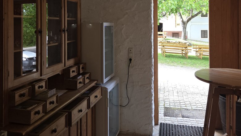 The Krottendorfer family's cycling rest stop, © Winzerhof Krottendorfer Interior with wooden furniture and view outside onto a terrace with benches.
