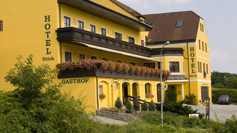 Hotel Stich, © Familie Stich Yellow hotel building with flowers on the balcony.