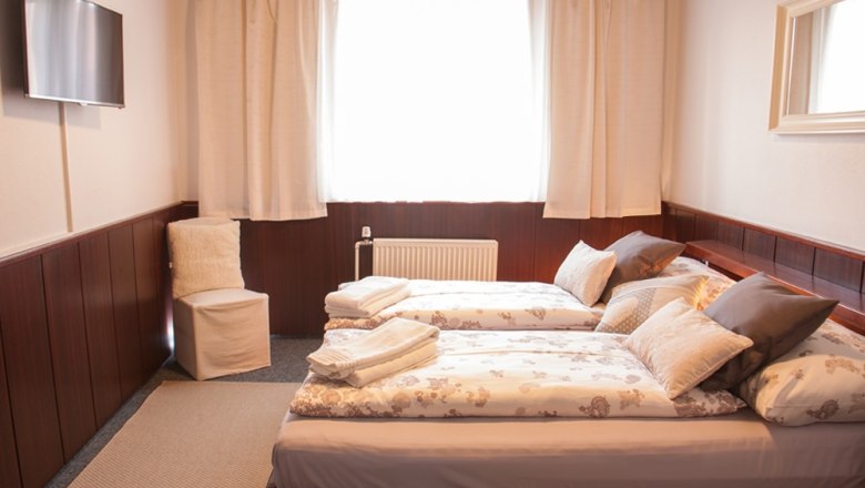 Pension Brandl, © Karin & Herbert Brandl Comfortable hotel room with two single beds, TV, chair and window with curtains.