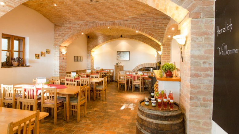 Wine tavern Müllner, © Astrid Bartl Interior view of a cozy wine tavern with wooden tables and brick walls.