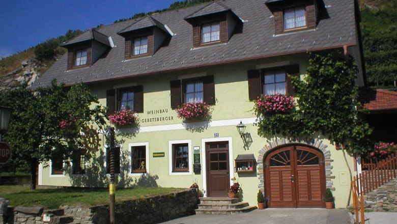 Winery Gebetsberger Exterior view of the winery, © Gebetsberger Exterior view of a winery with yellow facade and flowers.
