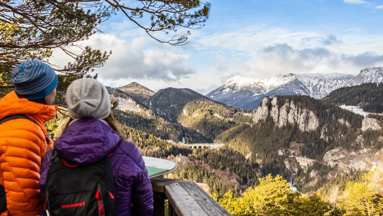 "20-shilling view" - hike for every season, © Wiener Alpen - Martin Fueloep Two people looking at a mountain landscape with a viaduct.