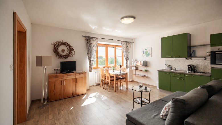 Guesthouse-Winzerhof Bernhard, © Jolly Schwarz Bright living room with green kitchen, dining table and sofa.