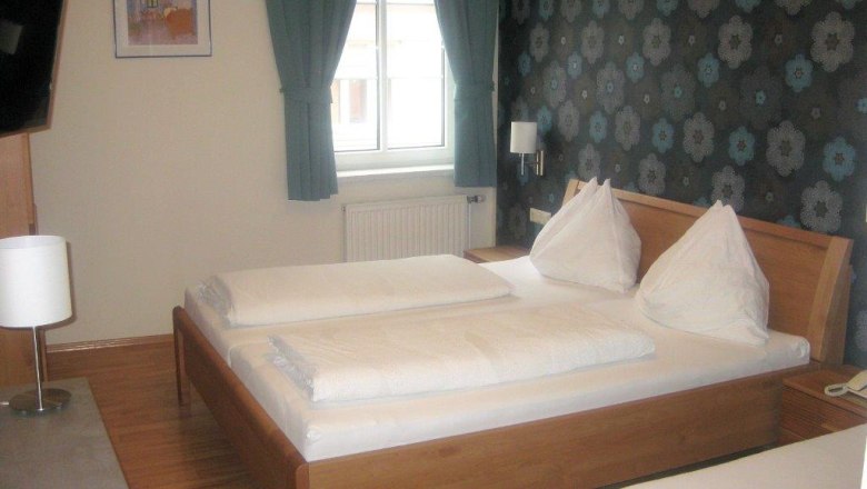 Braugasthof Adlerbrau, room, © Braugasthof Adlerbräu Hotel room with double bed, flowery wallpaper and windows with green curtains.
