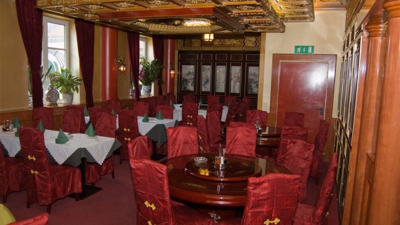 Indoor area, © Chinarestaurant Evergreen Elegant restaurant with red chairs and decorative ceiling.