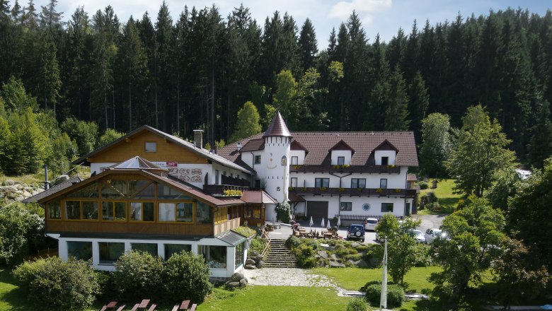 Fairytale Hotel Waldpension Nebelstein, © Andreas Schmidt A hotel in the forest with a tower and garden.