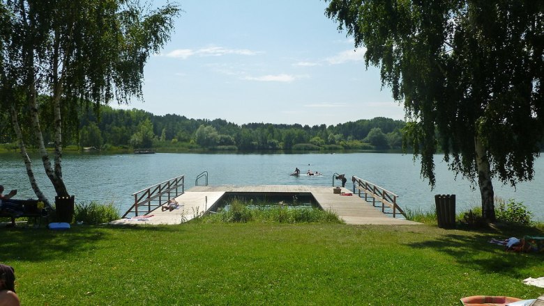 Langau mining lake, © Gemeinde Langau A jetty at Bergwerksee Langau with people swimming and sunbathing. Surrounded by trees and green meadows.