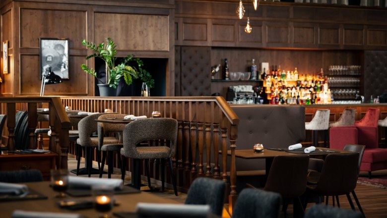 Zündwerk Living Room, © DERENKO DESIGN Elegant restaurant with wooden furniture, bar and subdued lighting.