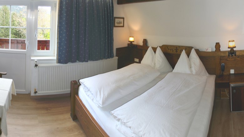 Apartment 1, © Marianne Gschaider Cozy bedroom with double bed, wooden furniture and window with a view of the greenery.