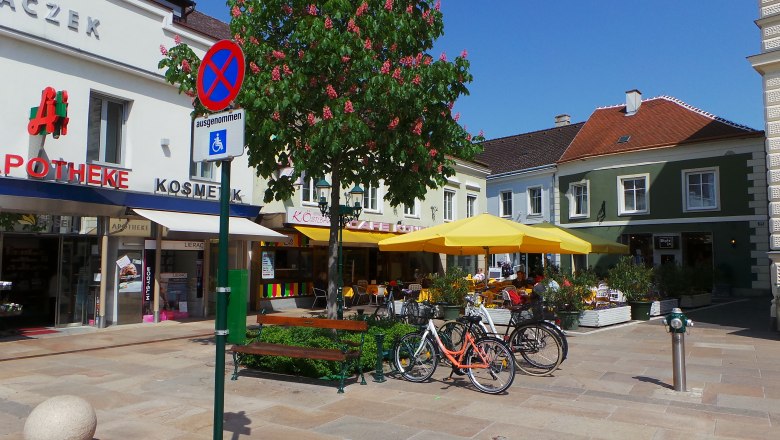 Exterior view, © Zehetmayer Street scene with pharmacy, café and yellow parasols.