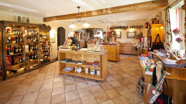 Poppy store, © Waldviertler Mohnhof Interior view of a cozy store with wooden shelves displaying wine bottles and other products. Decorations with poppies are visible.