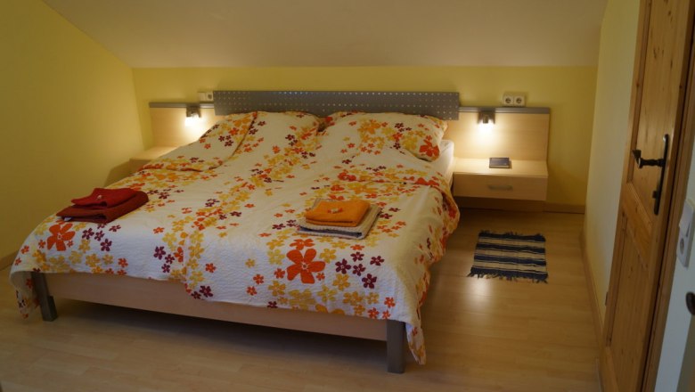 Maple room with private sanitary facilities, © Reep Comfortable bedroom with double bed, colorful floral bedding and bedside tables with lamps.