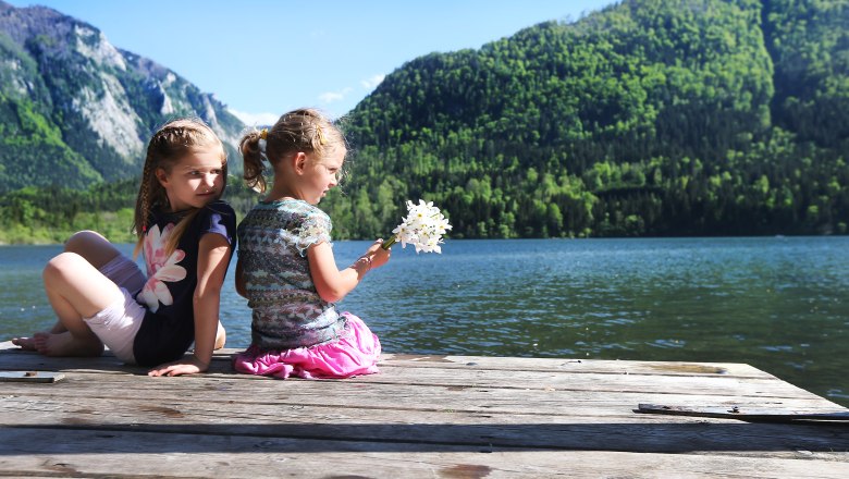 Enjoy nature at Lake Lunz, © weinfranz.at Two children sitting on a jetty on Lake Lunz with mountains in the background.