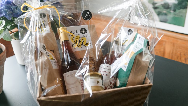 Farm store at the Zehetbauer vacation nest, © heiter-weiter.at/Karl Stangl Gift basket with regional products, wrapped in foil, on a table.
