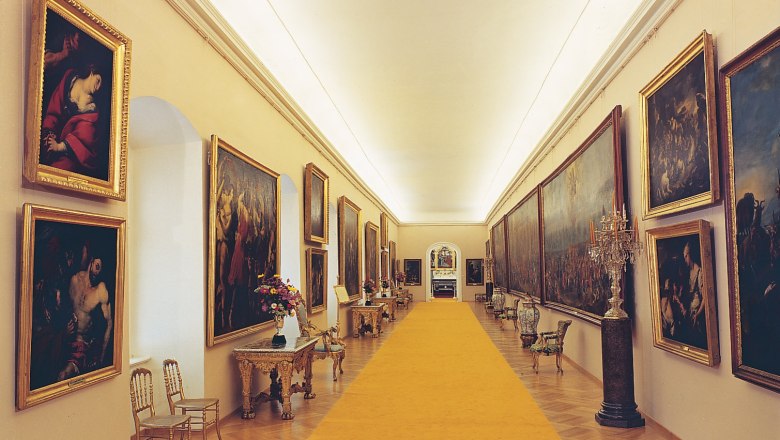 Rohrau Castle Picture Gallery, © Schloss Rohrau Long, elegant gallery space with paintings on the walls and a yellow carpet in the middle.
