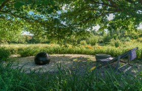 Altenburg Abbey, © Martina Draper A garden with a black ball, a deckchair and blossoming flowers under a tree.
