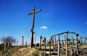 Freedom cross in Haugsdorf, © Weinstraße Weinviertel Wooden cross on a hill with vines and blue sky in the background.