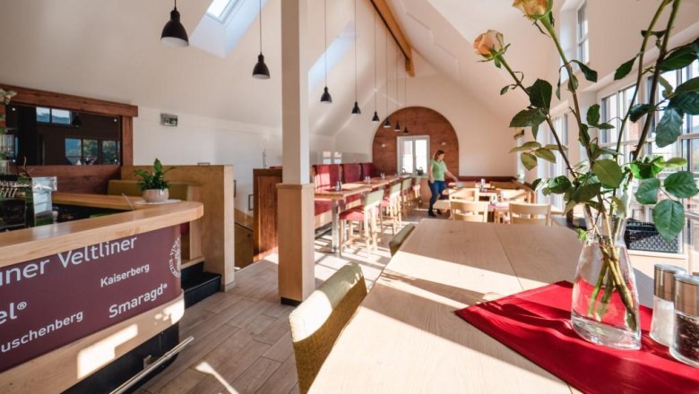 Wine tavern Kropf, © Alexander Pfeffel Interior view of a modern wine tavern with wooden furniture and large windows.