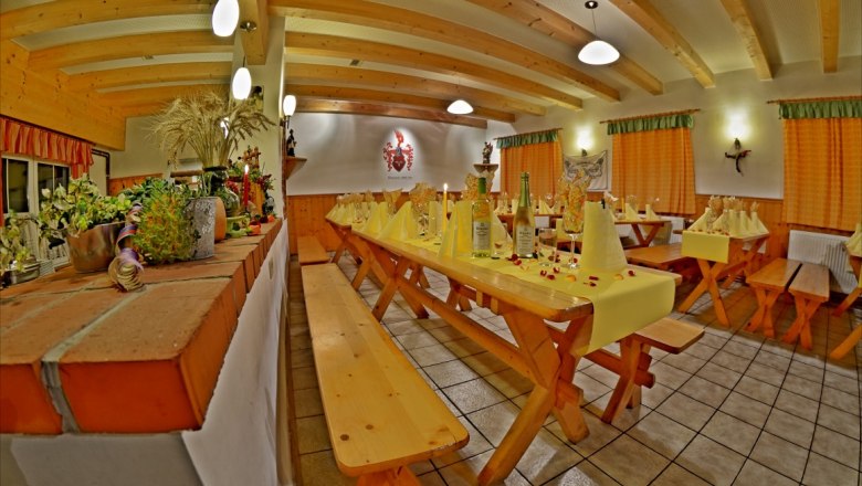 Viticulture Häusler, © zur Verfügung gestellt: Weinbau Häusler Cozy dining room with wooden tables, decorated with wine bottles and yellow napkins.
