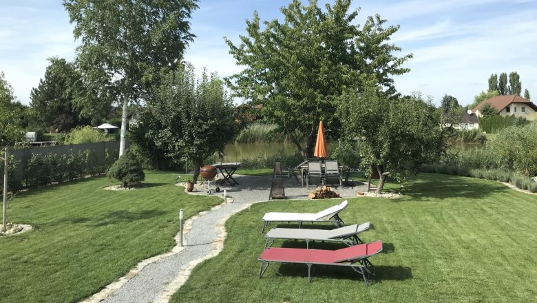 Garden, © Familie Mokesch A well-kept garden with lawn, trees, sun loungers and a table with parasol.