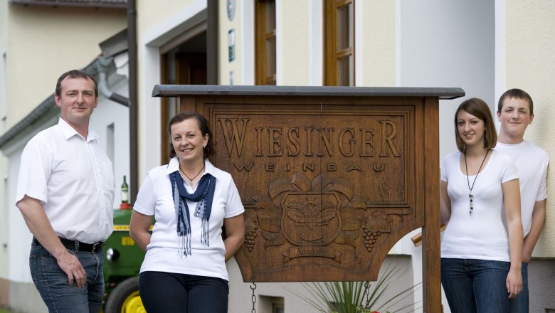 The Wiesinger family, © Michael Himml Four people are standing in front of a sign that reads 'Wiesinger Weinbau'.
