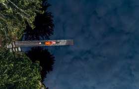 Bull pond, © Waldviertel Tourismus, Melanie Többe Two people are lying on a footbridge over a dark pond, surrounded by trees.