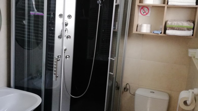 Bathroom, © Kesper Modern bathroom with shower cubicle, washbasin, toilet and shelf with towels and toilet paper.